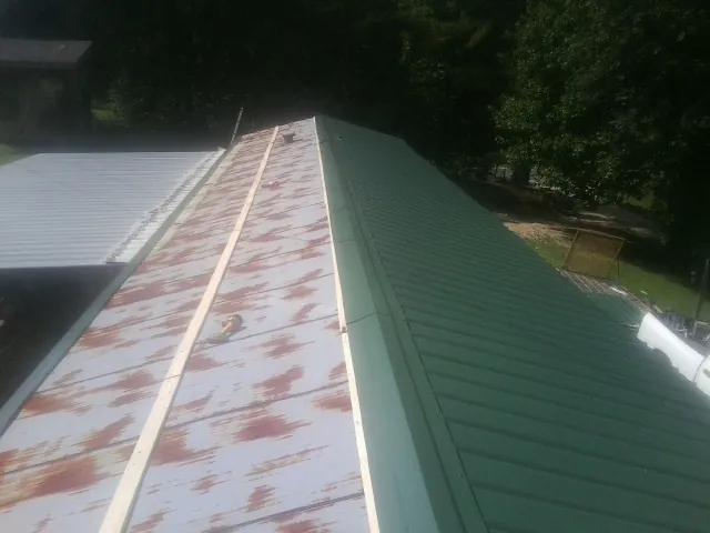 Old rusted panels beside newly installed green metal roofing — Wind Damage Roof Repair by Roofing Brothers in Northbrook