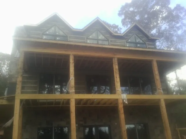 Dormers and porch framing on a large log home under construction — Roof Coating work by our crew in Northbrook